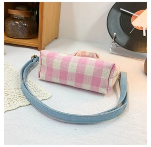 Close-up of pink checkered canvas kids bag with blue denim straps and metal buckles