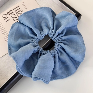 Detailed view of blue fabric scrunchie with soft pleated texture on white background