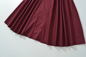 Detail of wine red French style dress showing pleated fabric texture and sleek finish