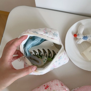Close-up of pink floral quilted makeup bag with hair clips showing inner storage