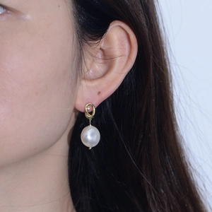 Detailed close-up of a white pearl drop earring with a golden twisted rope metal stud on ear