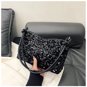 Close-up of black sequin baguette bag with knotted leather handle and silver zipper detail