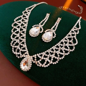 Close-up of teardrop crystal necklace and earrings set on green velvet background