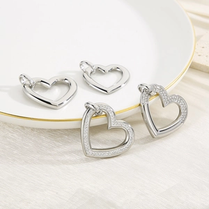Detailed view of silver heart pendants with polished and diamond-set finishes on a tray
