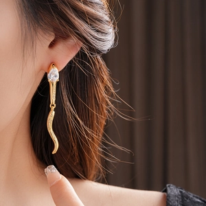Golden snake earrings with zircon drop on model, luxury vintage jewelry detail