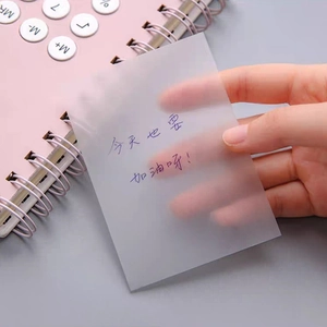 Transparent sticky notes for students held over a notebook with calculator on pink background