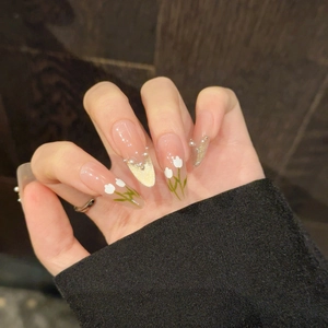 Détail de faux ongles tulipe faits main avec perles 3D et touches de paillettes dorées