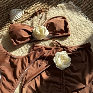 Detail of a brown bikini set featuring 3D white camellia flowers on textured fabric