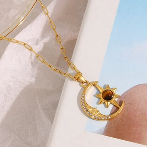 Close-up of celestial gold necklace with moon and sun pendant on lifestyle background