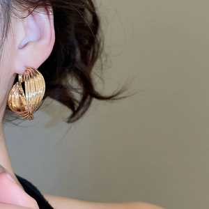 Close-up of gold layered hoop earrings on model highlighting a textured metallic design