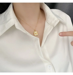 Close-up of gold butterfly pendant with white shell inlay on a necklace chain