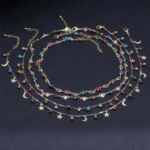 Close-up of golden multi-layer anklets featuring colorful heart and moon charms