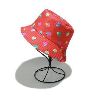 Close-up of red sun hat with colorful mushroom print on a black metal display stand