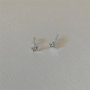 Detail of silver star stud earrings with black outlines and silicone backings