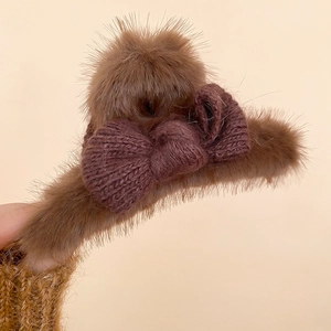 Detail of plush brown hair claw clip with a cozy knitted bow and fuzzy texture