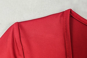 Detail view of red knitted dress neckline showing tight stitching and elastic fabric