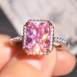 Detailed close-up of a pink radiant cut crystal ring with halo and pavé diamond band