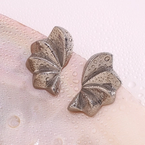 Macro shot of silver geometric petal earrings with realistic water droplets on surface