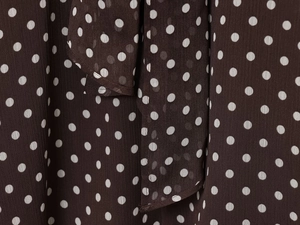 Macro shot of dark brown chiffon fabric texture with classic white polka dot pattern