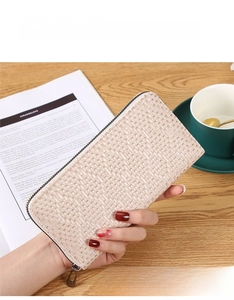 Detail of a champagne woven long wallet featuring a metal zipper and large capacity
