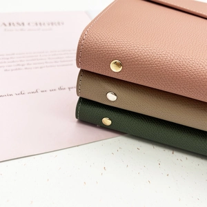 Close-up of litchi texture leather notebooks in pink, khaki and green with metal buckles