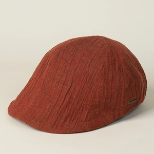 Detail of vintage linen flat cap with textured vertical pleats and metal logo plate