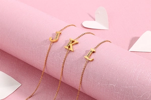 Close-up of gold chain necklaces with sparkling diamond-set J, K, and L letter pendants