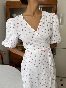 Detail of white cotton floral wrap dress with puff sleeves and waist tie fastening