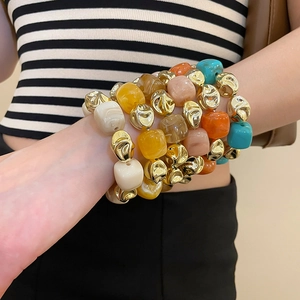 Close-up of colorful irregular acrylic beads and gold metal spacers on model wrist