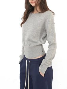 Close-up of grey wool knit top with decorative side buttons and ribbed cuff details