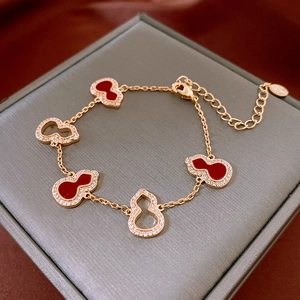 Detail of gold gourd bracelet with red enamel and white zircon on jewelry box