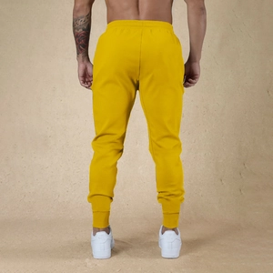 Vista trasera de pantalones deportivos amarillos para hombre con puños ajustados