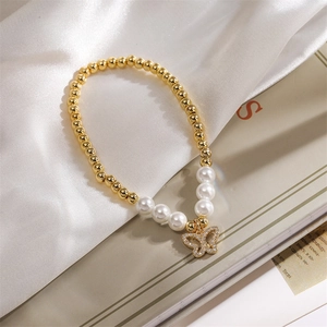 Detail of gold beads and white pearls bracelet with a zircon butterfly charm on silk