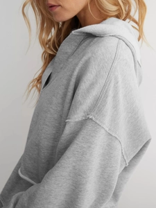 Detail eines grauen Hoodies mit überschnittenen Schultern und offener Kantenverarbeitung