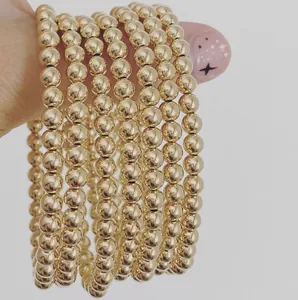 Detail of multi-layer gold stainless steel beaded bracelet worn on wrist with natural pearls