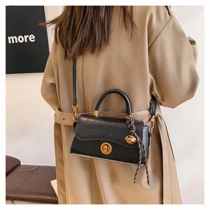 Detail of black matte crossbody bag with gold rotary lock and silk scarf on the handle