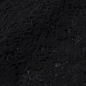 Vue macro d'un tissu de dentelle florale noire complexe avec motifs découpés délicats