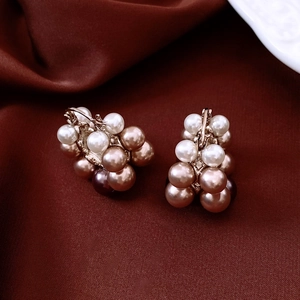 Macro detail of French vintage pearl earrings with gold accents on silk background