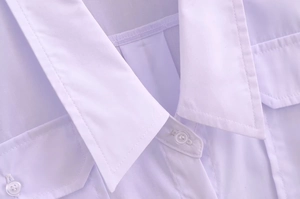 Detailed close-up of V-neck collar with white buttons and front pocket on blouse