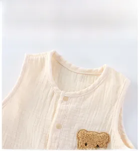 Detail of baby cotton gauze vest featuring soft bound neckline and cute bear applique