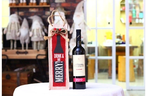 Christmas burlap wine bag with Drink & Be Merry slogan and pine cone decorations