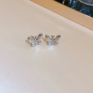 Macro shot of silver butterfly stud earrings in polished stainless steel for women
