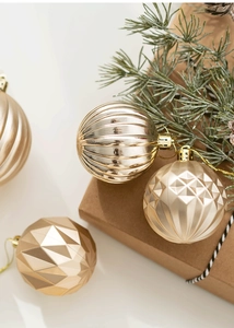 Gros plan de boules de Noël dorées avec textures rayées et géométriques dans une boîte cadeau