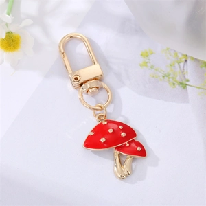 Detail of red and gold mushroom keychain with metallic finish on a decorative floral background