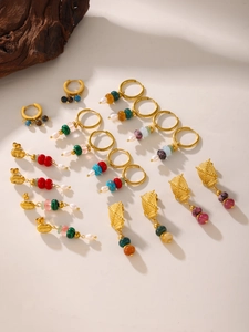 Detail of assorted gold drop earrings with colorful beads and white pearls in a set