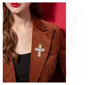 Macro shot of vintage golden cross brooch with opal and crystals on brown corduroy blazer