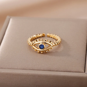 Macro detail of gold-plated evil eye ring with blue gemstone on velvet display