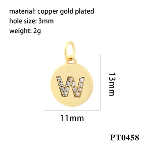 Macro detail of gold plated copper round pendant with cubic zirconia letter W inlay