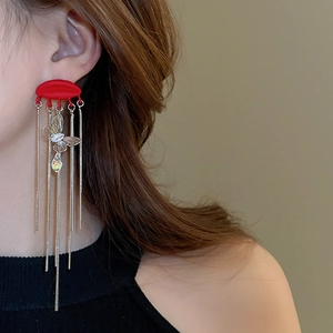Close-up of red butterfly tassel earrings with crystal drop pendant worn by model