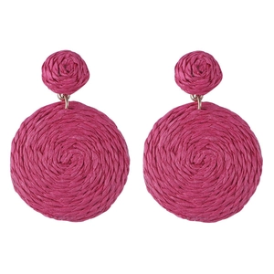 Macro detail of magenta raffia woven earrings showing texture and craftsmanship